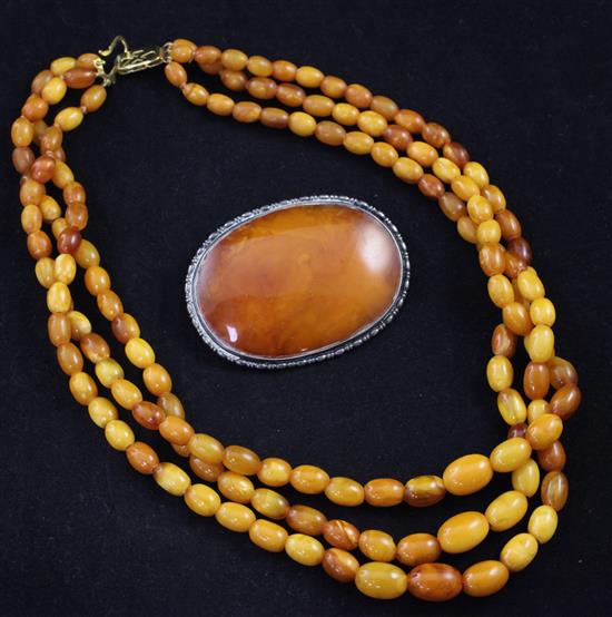 A triple strand graduated oval amber bead necklace and a silver mounted amber brooch, brooch 2.25in.